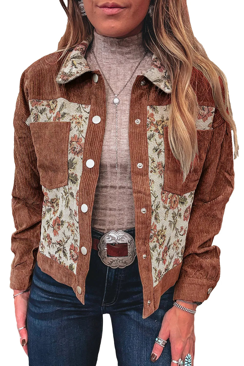 Woman wearing a brown corduroy jacket with floral patterns and blue jeans.