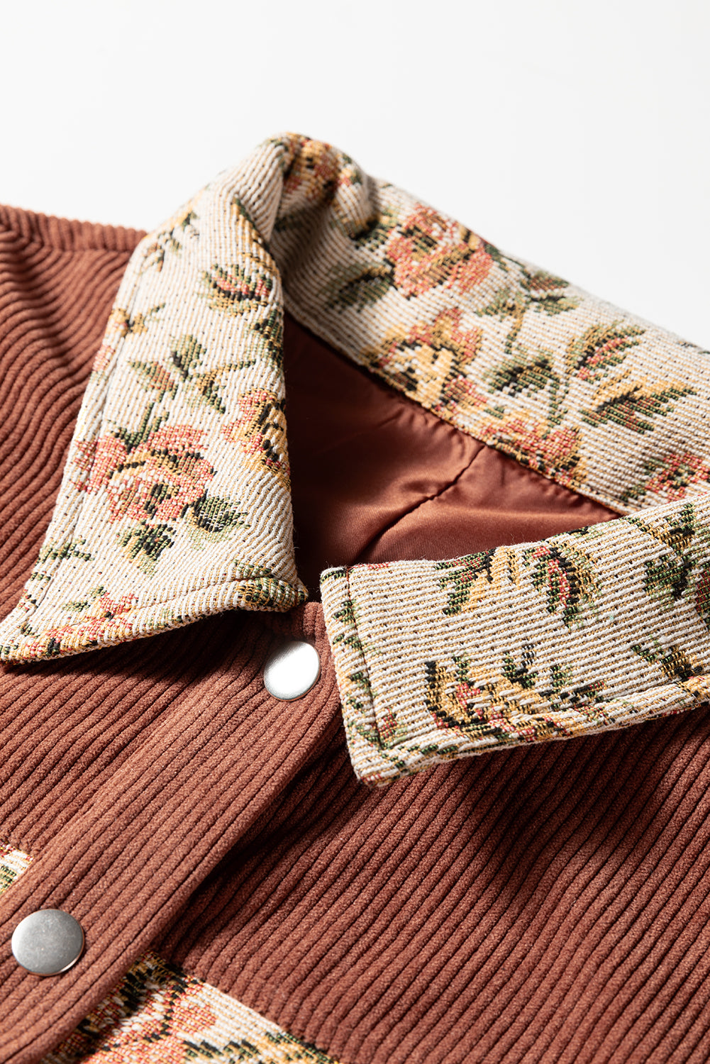A photo close up of a ribbed brown floral patch work collar jacket with snap buttons.
