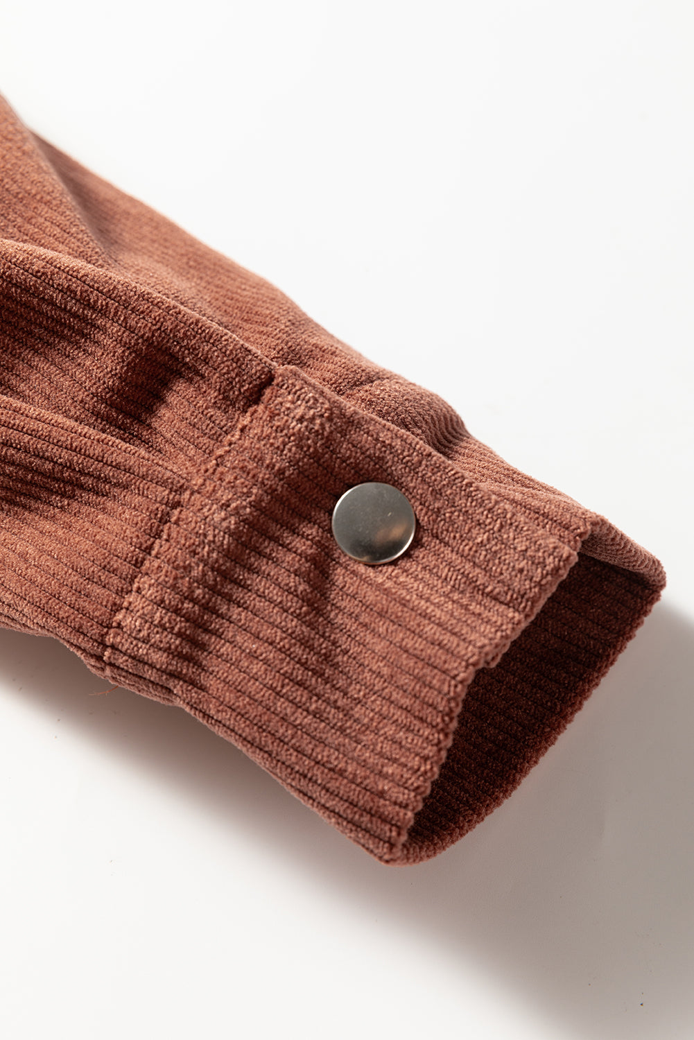 A photo of a ribbed long sleeve cuff with silver snap button.