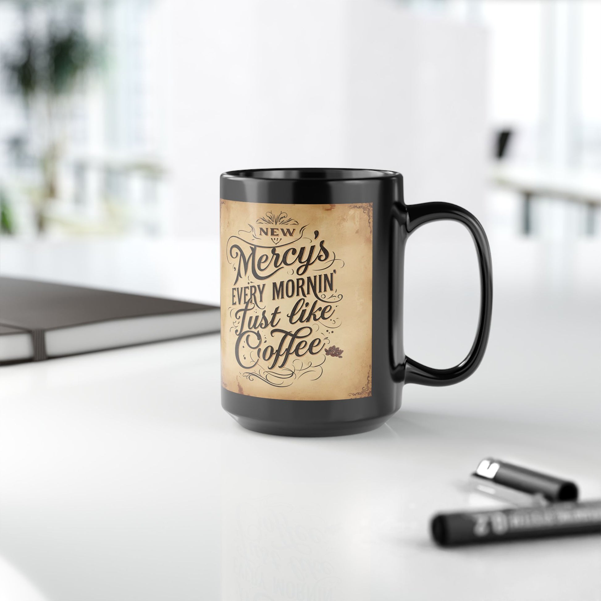 Black mug with vintage-style text design on a white surface with office items.