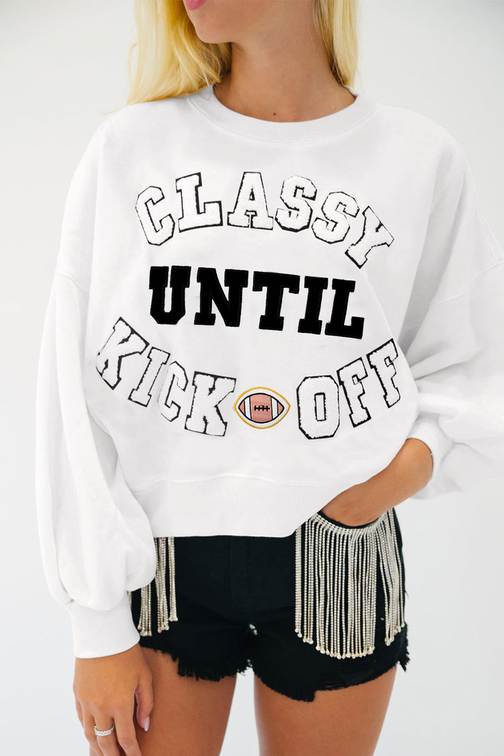 Person wearing a white sweatshirt with 'Classy Until Kick Off' text and black shorts.