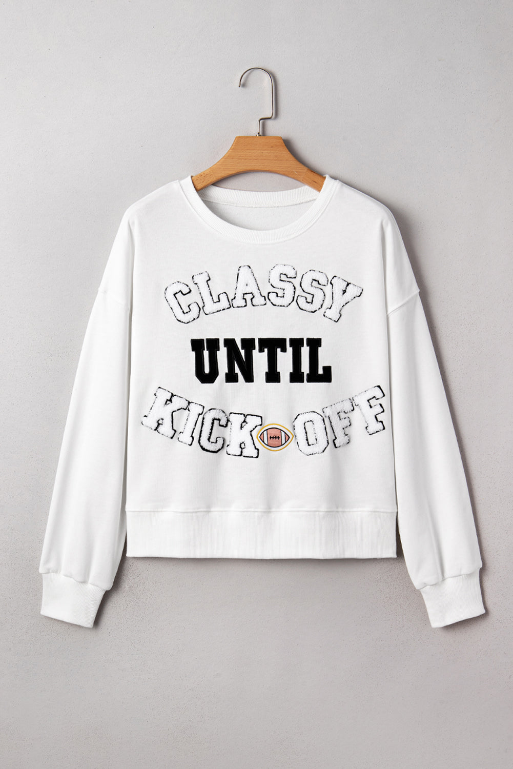 White sweatshirt with text 'CLASSY UNTIL KICK OFF' on a gray background