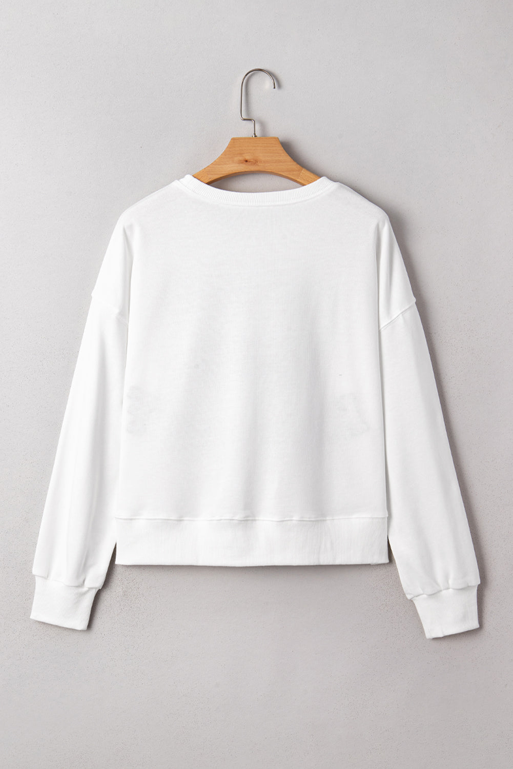 White sweatshirt on a wooden hanger against a gray background