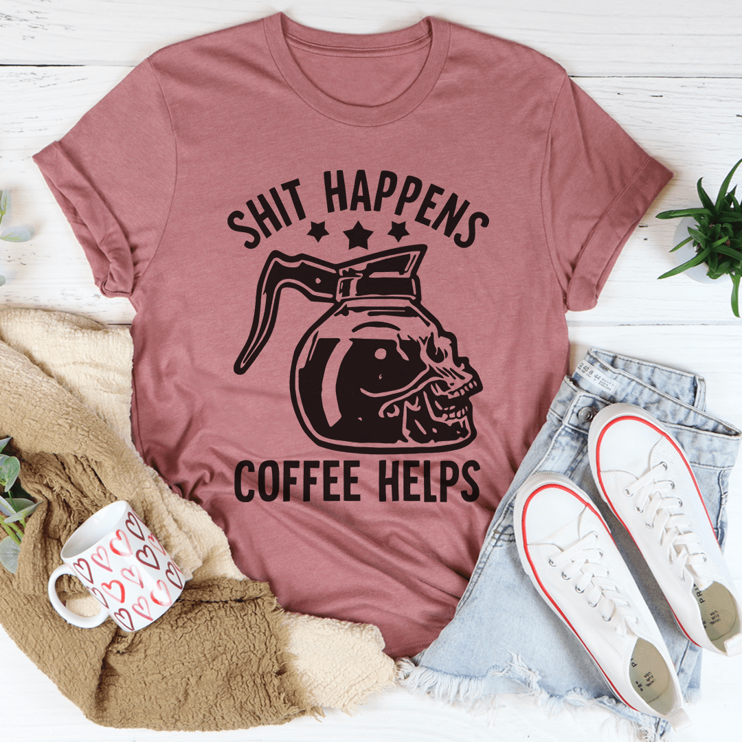 Mauve t-shirt with coffee-themed graphic and text, placed on a white surface with casual items around.