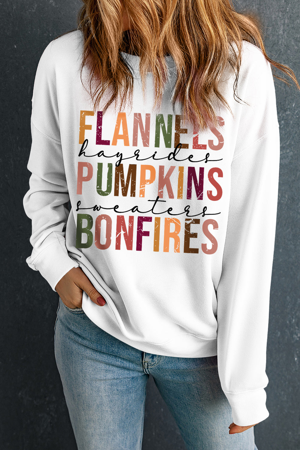 Person wearing a white sweatshirt with colorful text on a dark background