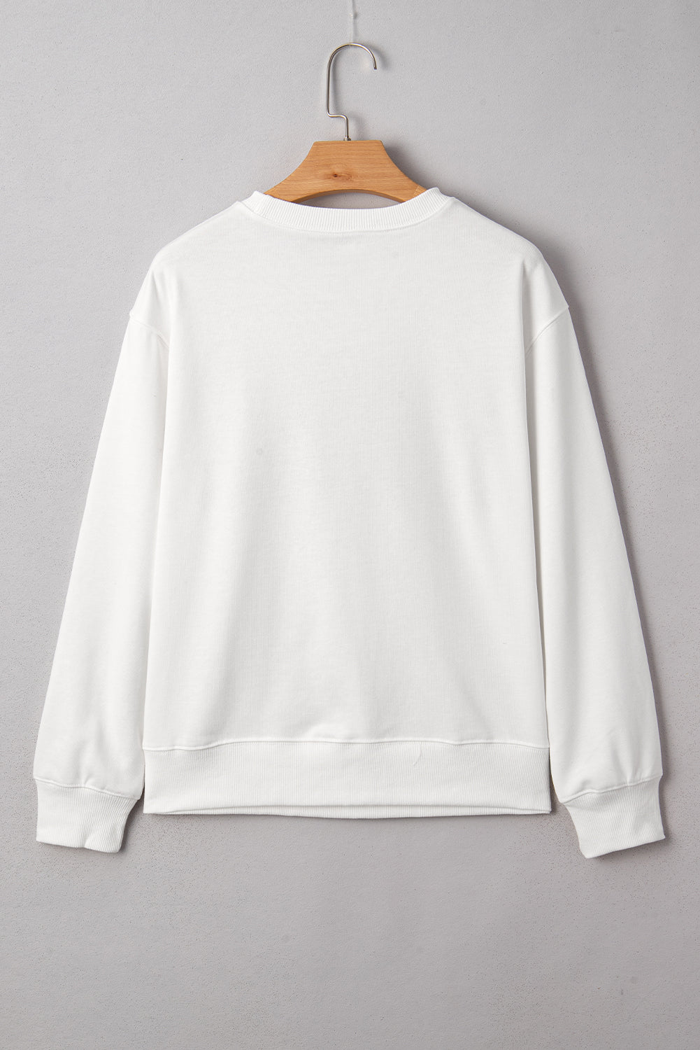 White sweatshirt on a wooden hanger against a gray background