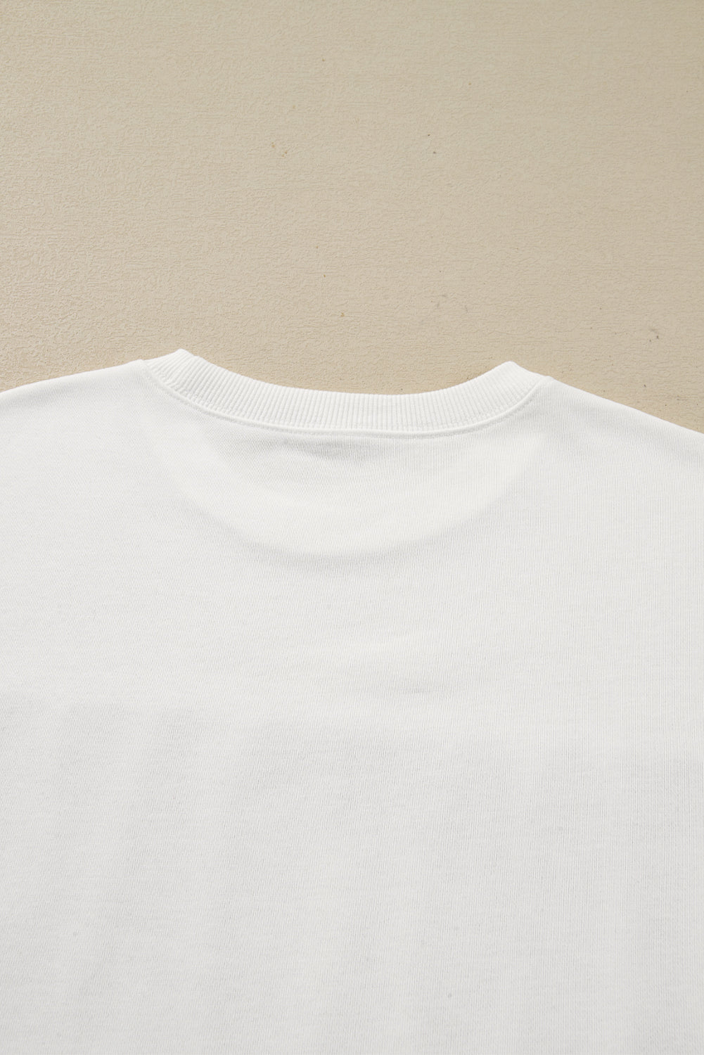 Close-up of a white t-shirt collar on a beige background
