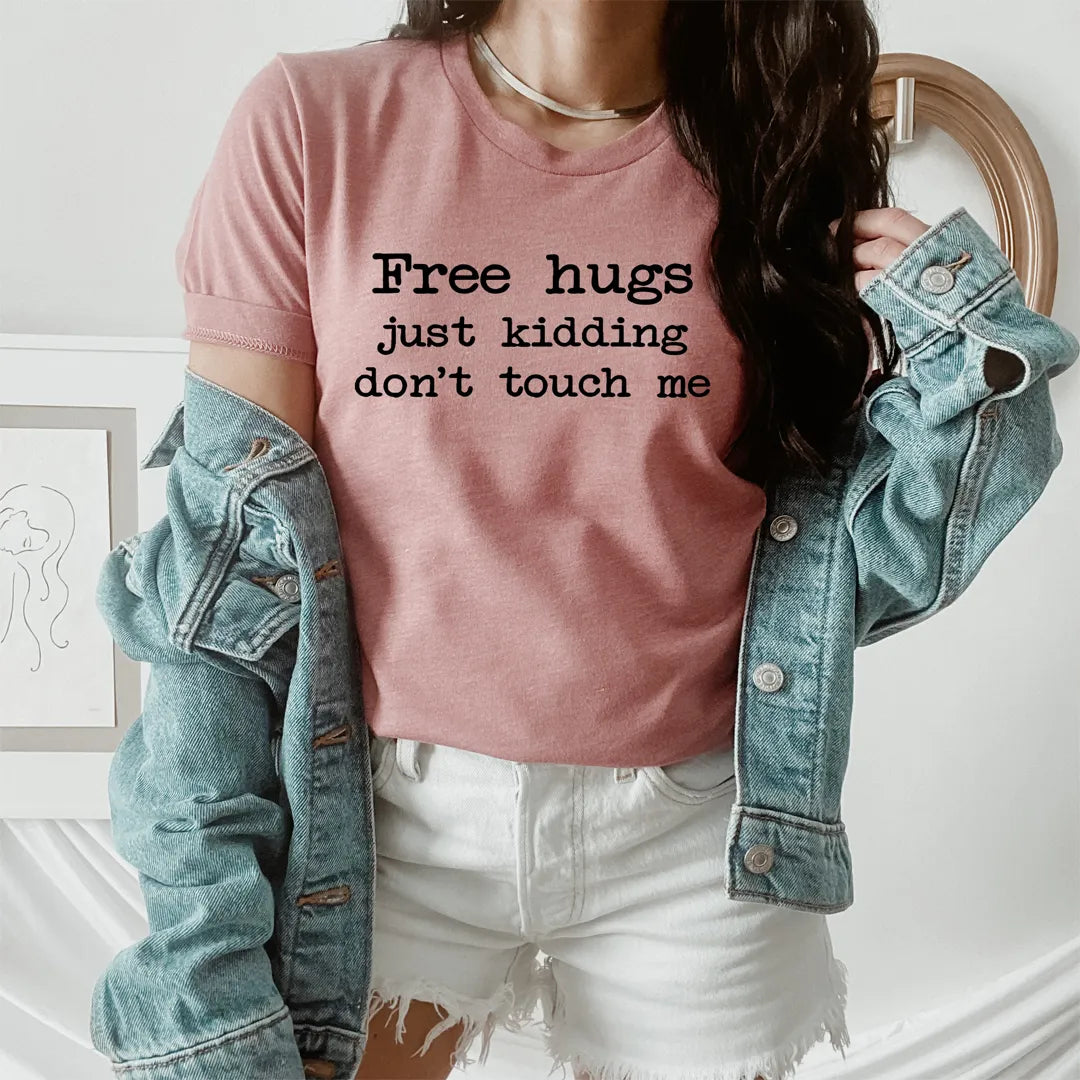 Person wearing a pink t-shirt with text and a denim jacket indoors.