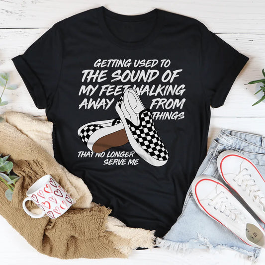 Black t-shirt with graphic and text on a white surface with casual items around
