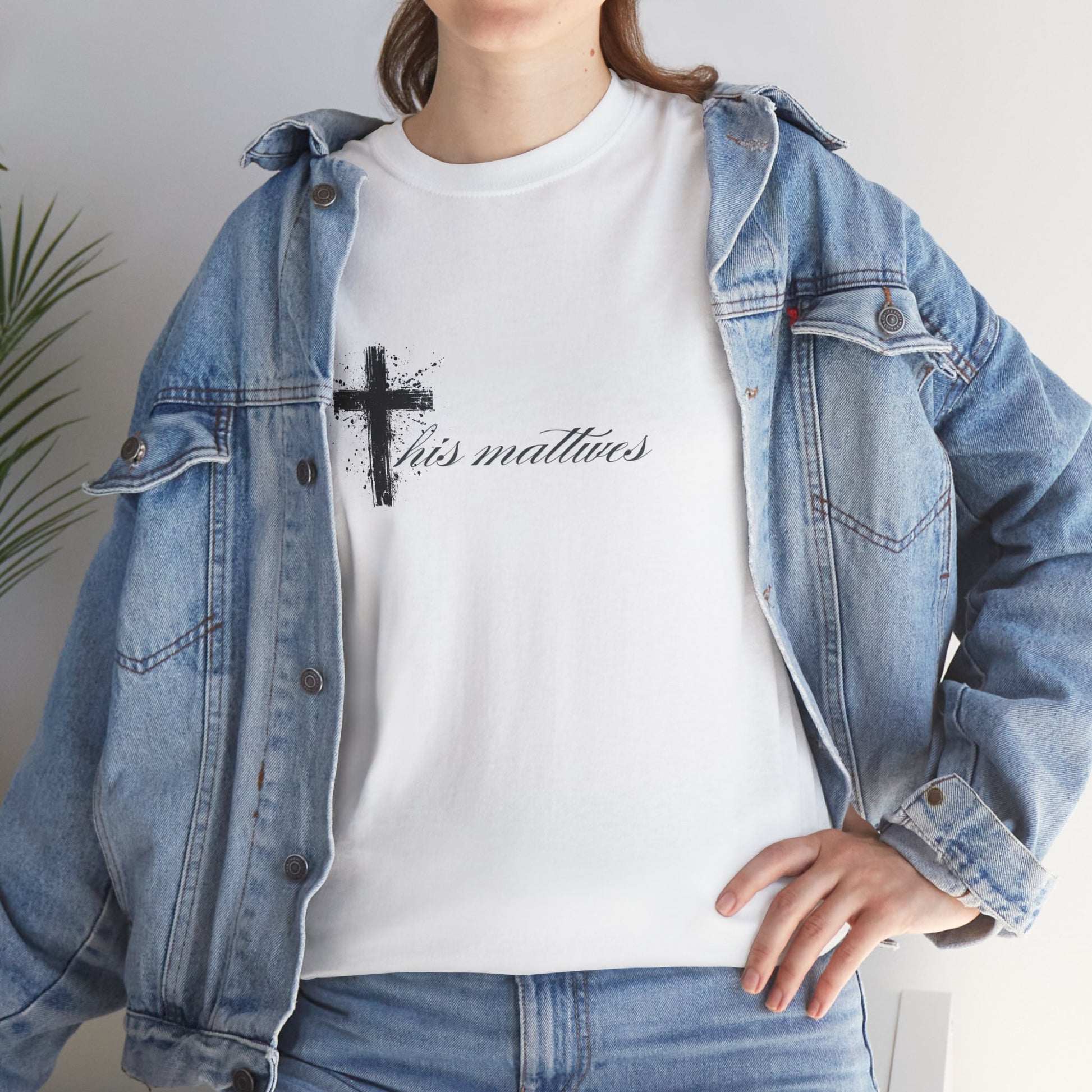 Person wearing a white t-shirt with a black cross and text, paired with a denim jacket.