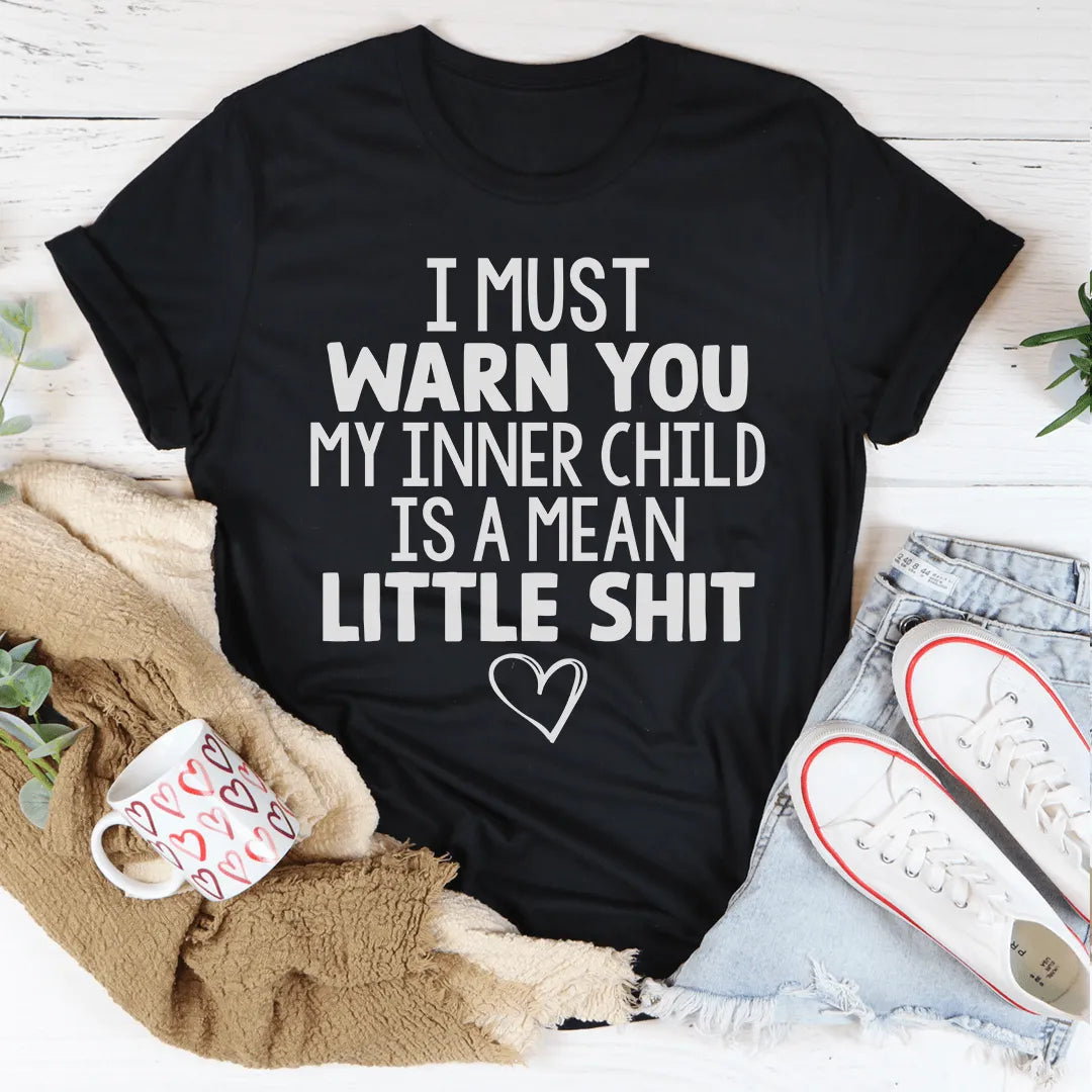 Black t-shirt with humorous text on a white surface with casual items around