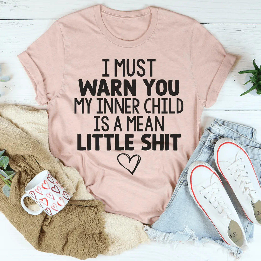 Pink t-shirt with humorous text on a white surface with accessories.