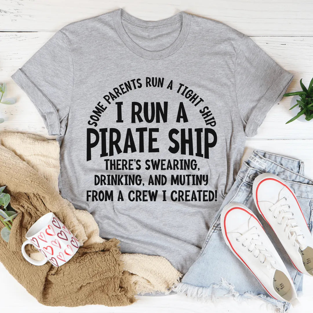 Gray t-shirt with humorous text design on a white surface with casual items around