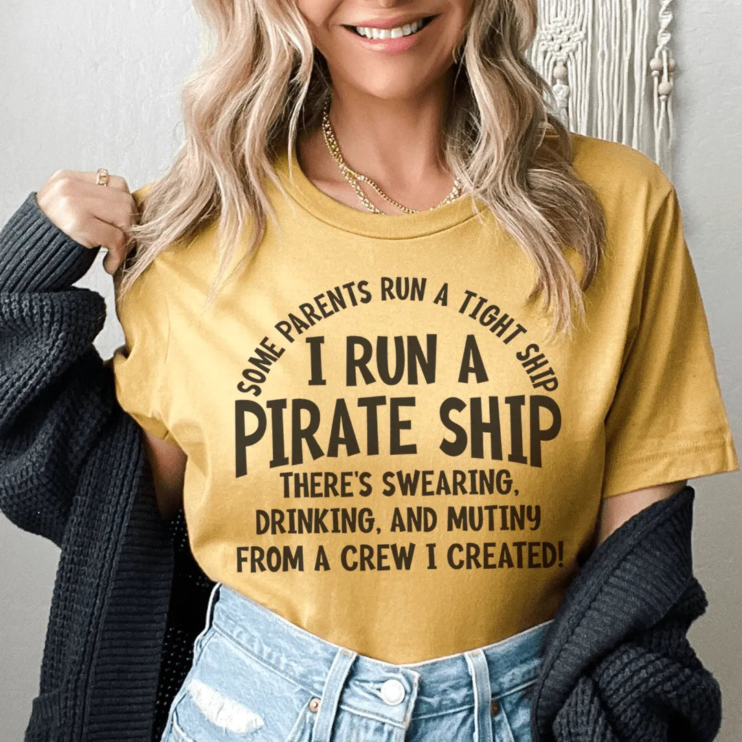 Person wearing a mustard yellow t-shirt with a humorous quote, standing against a neutral background.