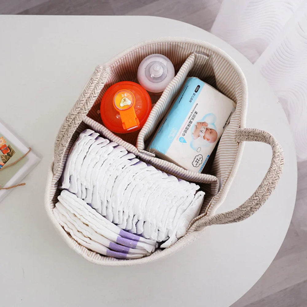 Oval-shaped basket with baby items including diapers and a bottle on a light surface.