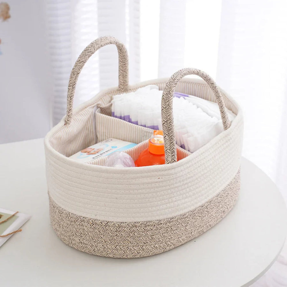 Beige woven basket with handles filled with baby items on a white surface.