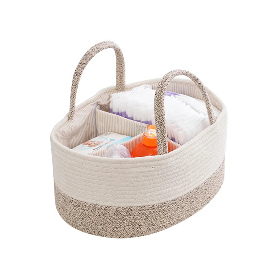 Beige woven basket with handles filled with baby items on a white background
