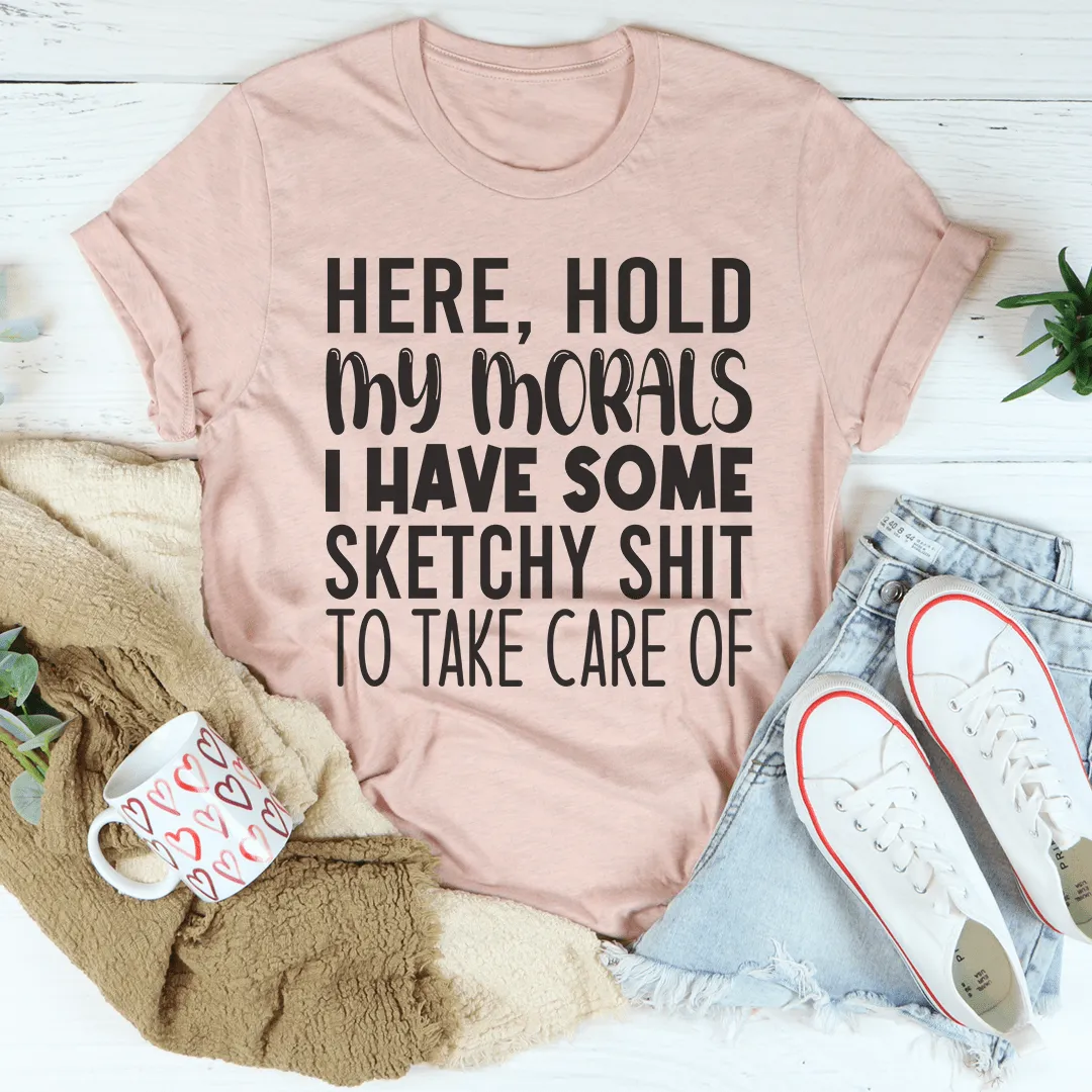 Pink t-shirt with humorous text, mug, shoes, and plant on a light wooden surface