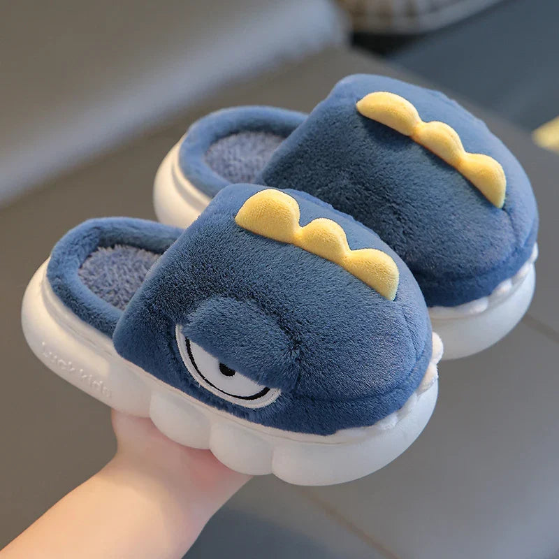 Blue children's slippers with yellow accents held by a hand on a neutral background
