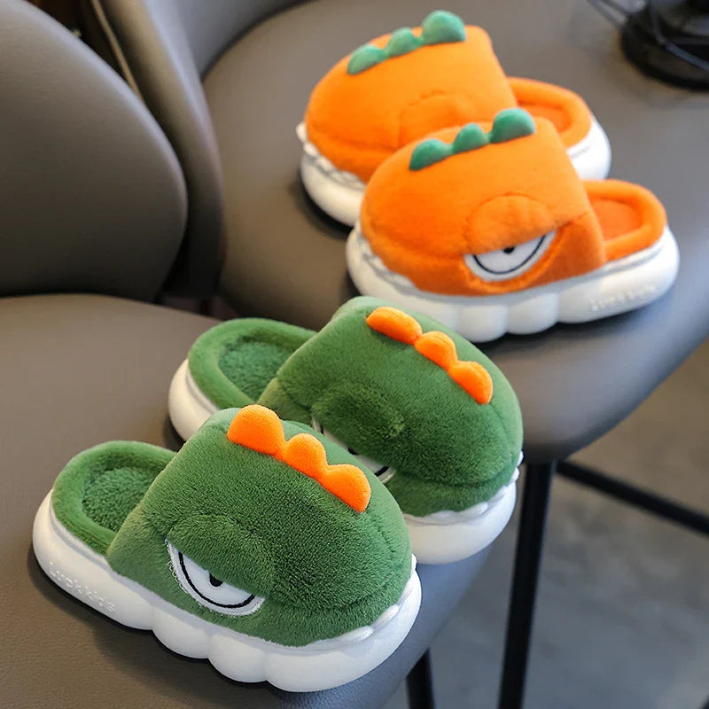 Pair of green and orange dinosaur-themed slippers on a chair.