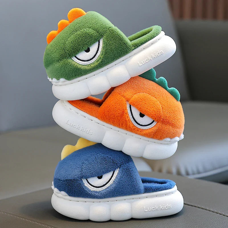 Stack of cartoonish plush slippers in green, orange, and blue on a neutral background.