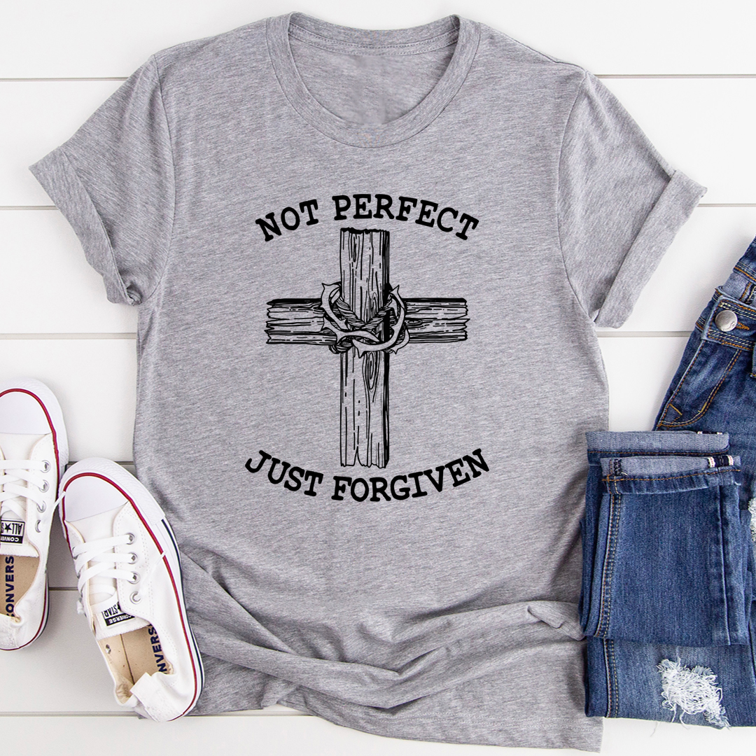 Gray t-shirt with cross design and text 'Not Perfect Just Forgiven' on a white surface with jeans and shoes.