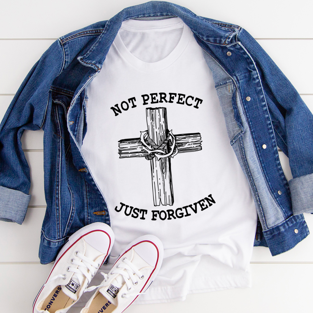 White t-shirt with cross design and text, denim jacket, and white sneakers on a light wooden floor.