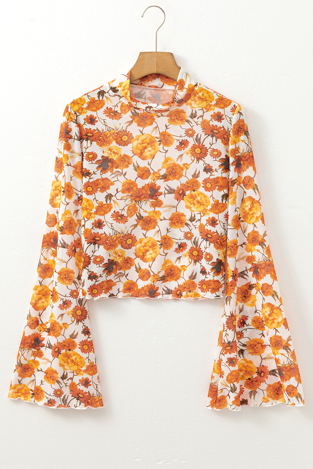 Floral blouse with bell sleeves on a hanger against a white background