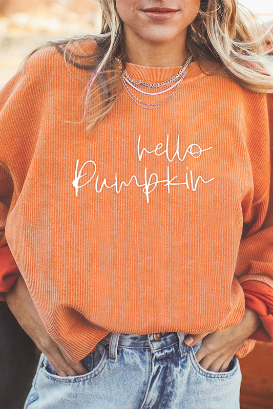 Person wearing an orange sweater with 'hello pumpkin' text, standing outdoors.
