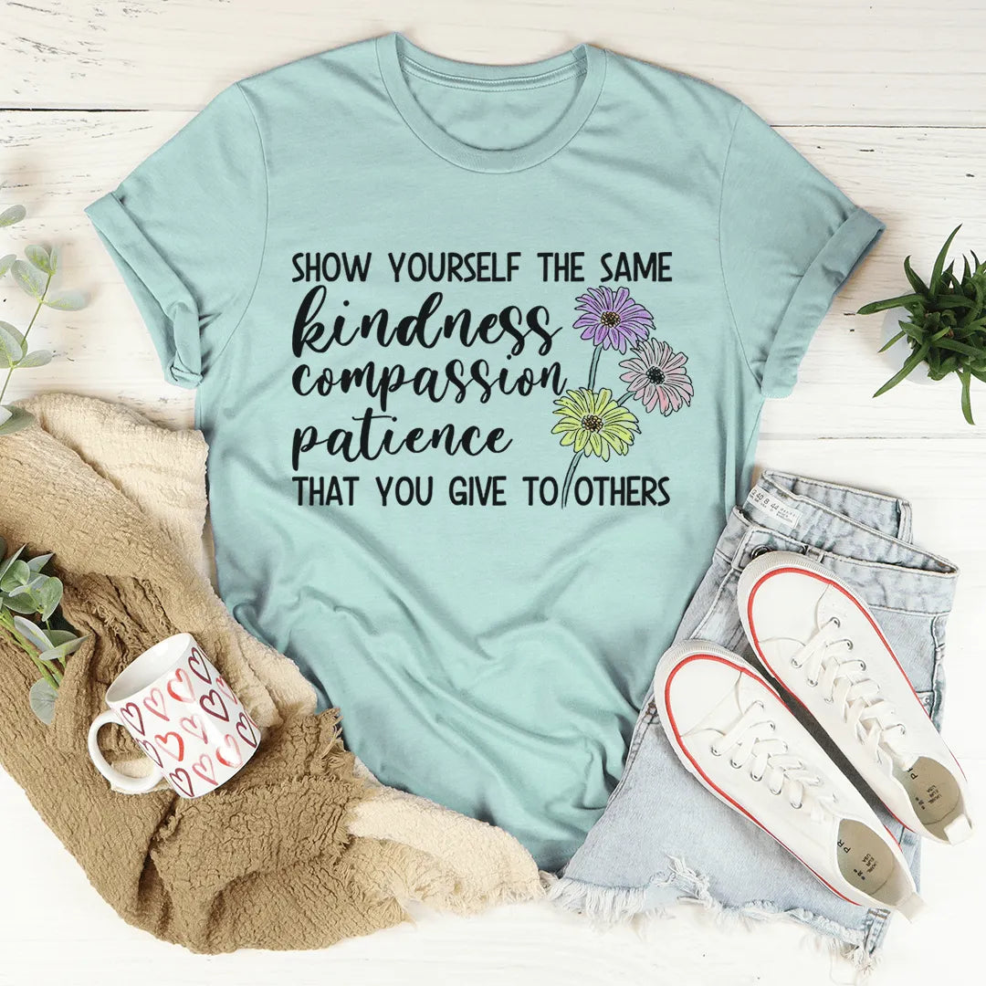Light blue t-shirt with motivational quote and flowers on a wooden surface with accessories.