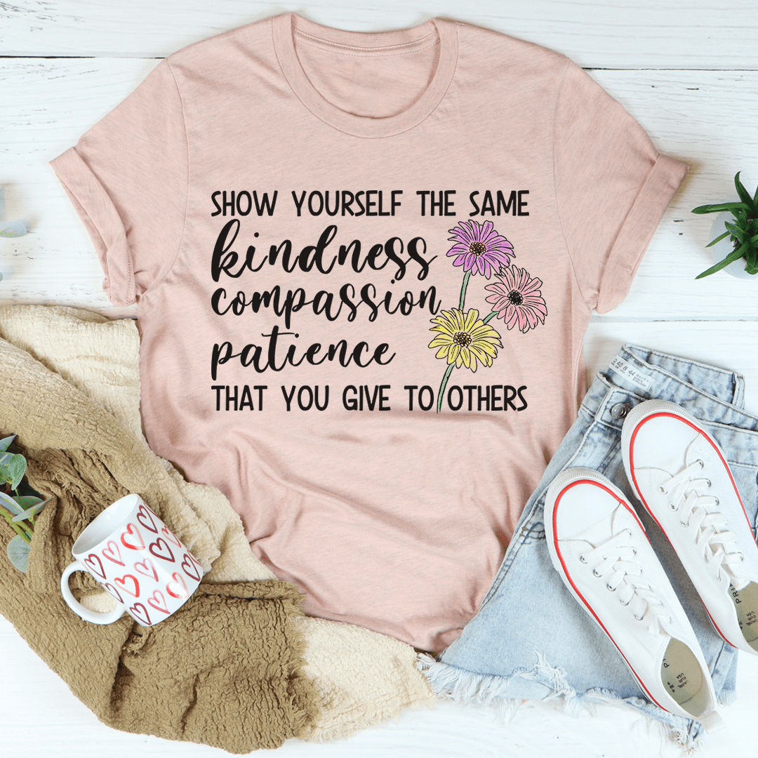 Pink t-shirt with motivational quote and flowers on a white surface with accessories.