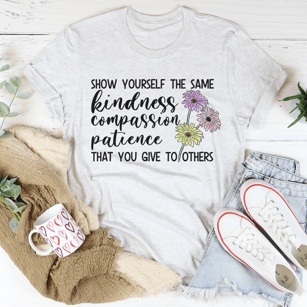 White t-shirt with motivational quote and flowers, surrounded by casual items on a light background