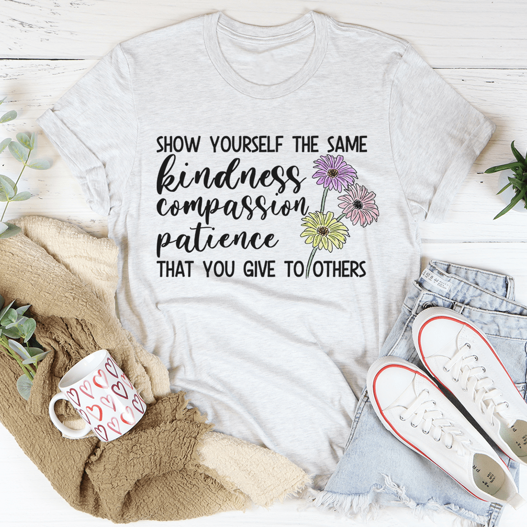 White t-shirt with motivational quote and flowers on a white background with casual items around