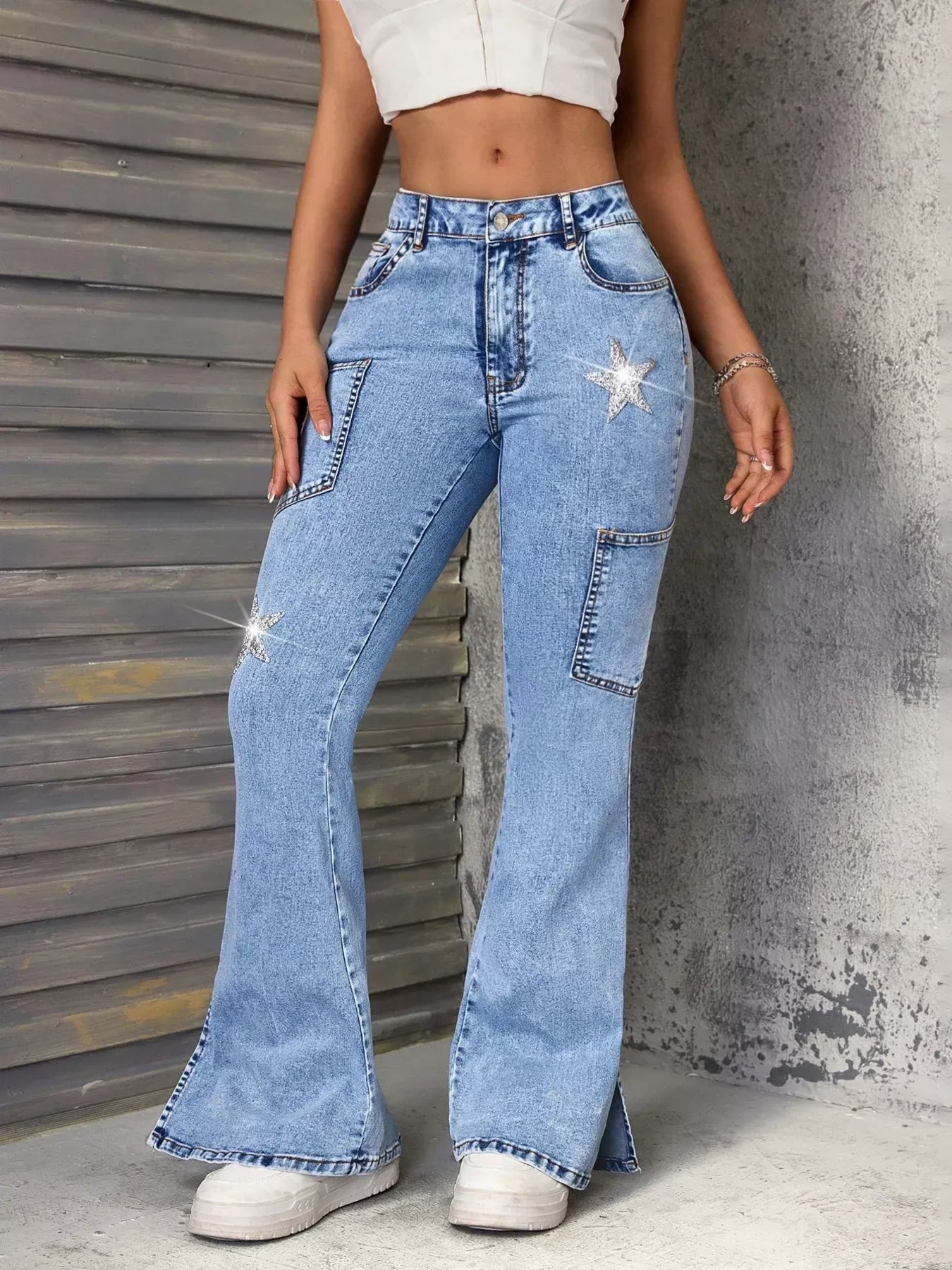 Person wearing high-waisted flared jeans with decorative elements against a textured wall.