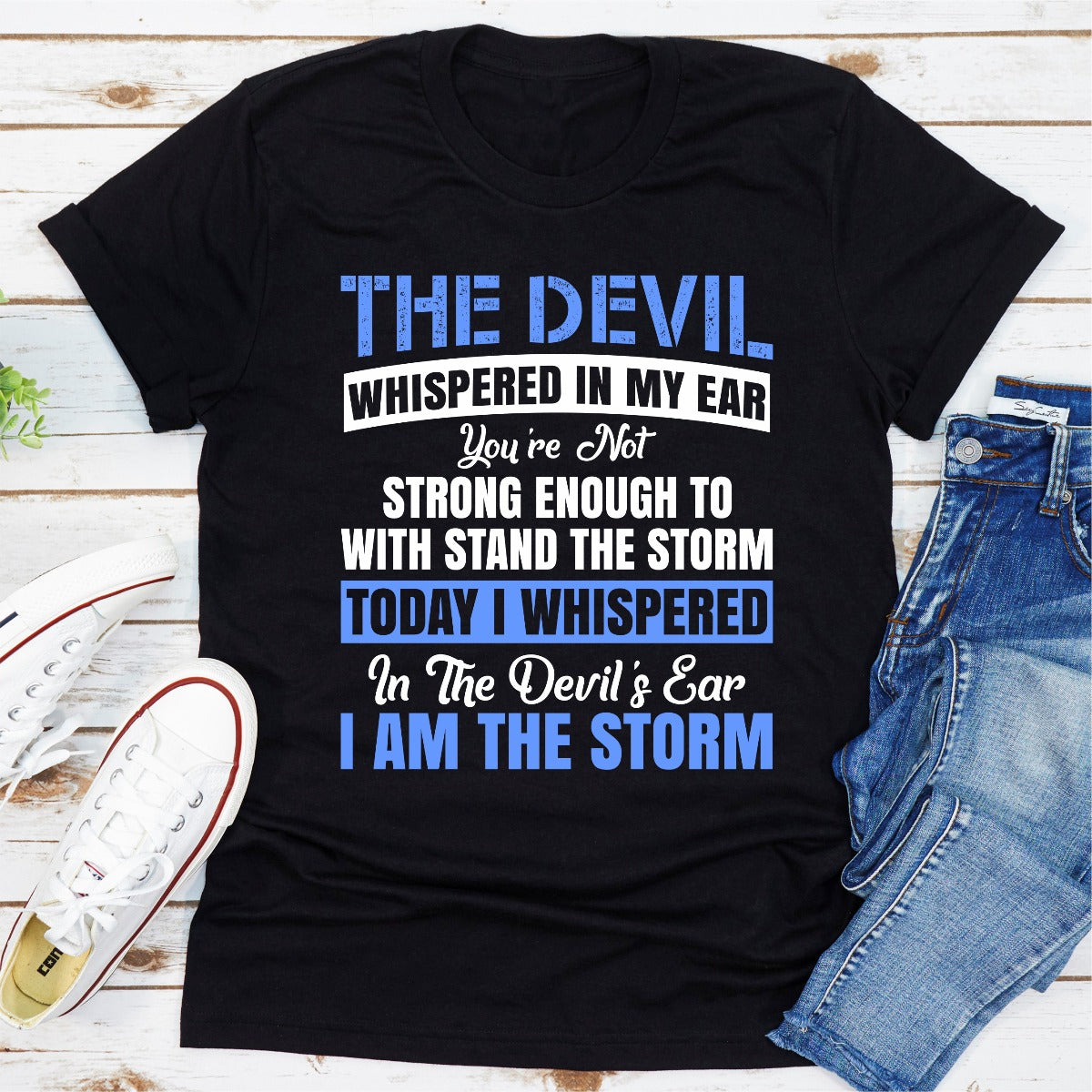 Black t-shirt with motivational quote on a wooden surface with jeans and sneakers.