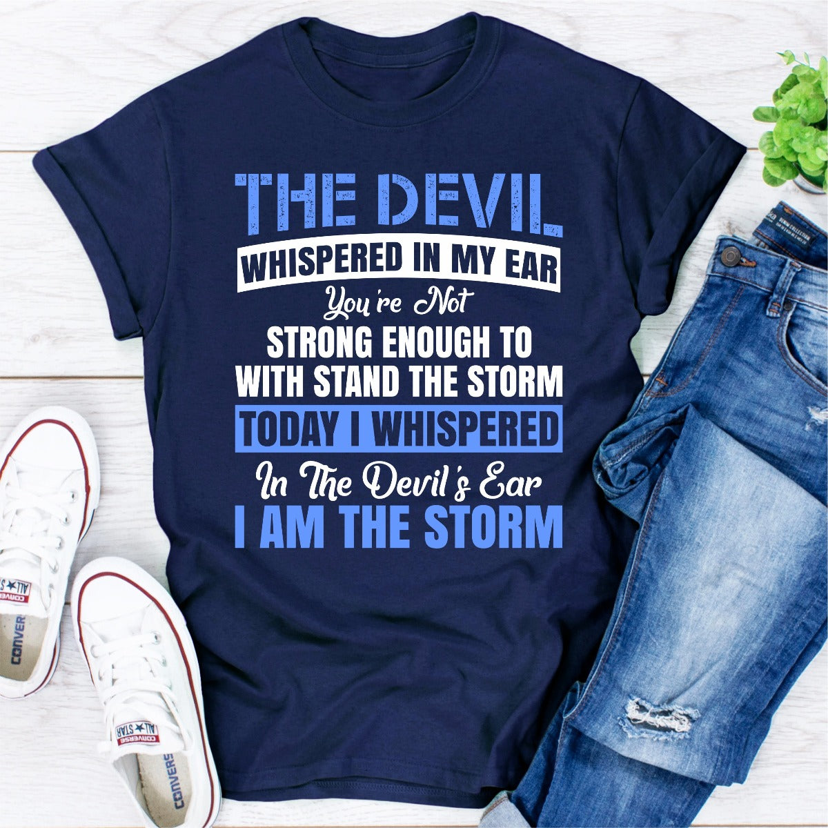 Navy blue t-shirt with motivational quote, paired with jeans and sneakers on a light wooden surface.