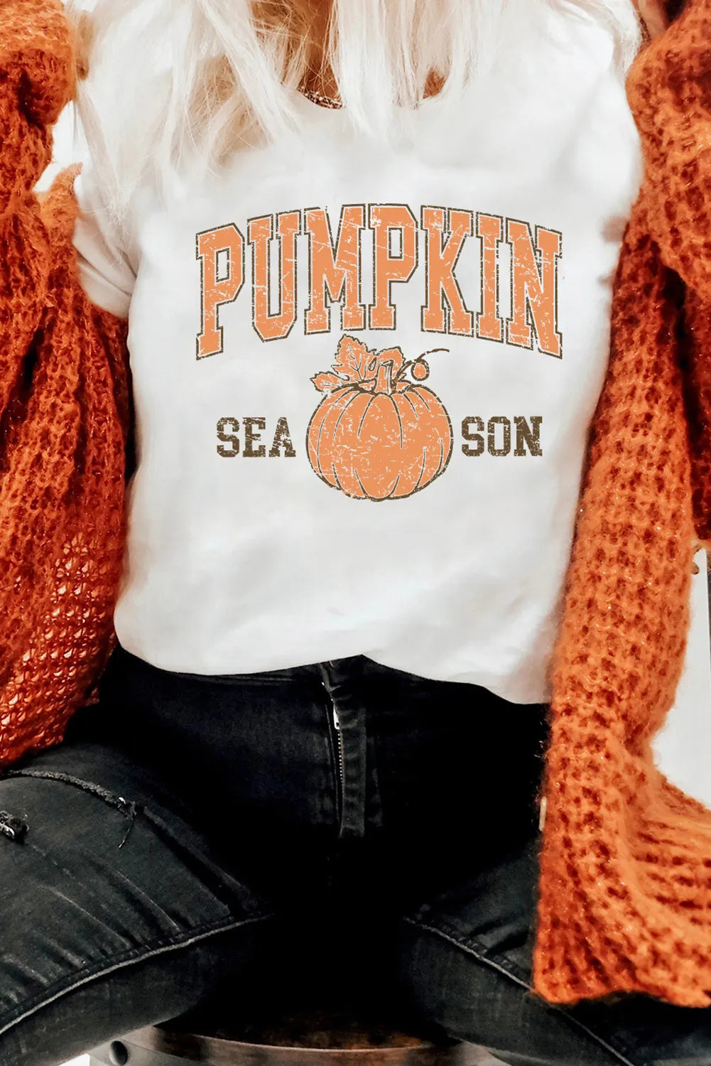 Person wearing a white t-shirt with 'Pumpkin Season' design, paired with an orange knit cardigan.